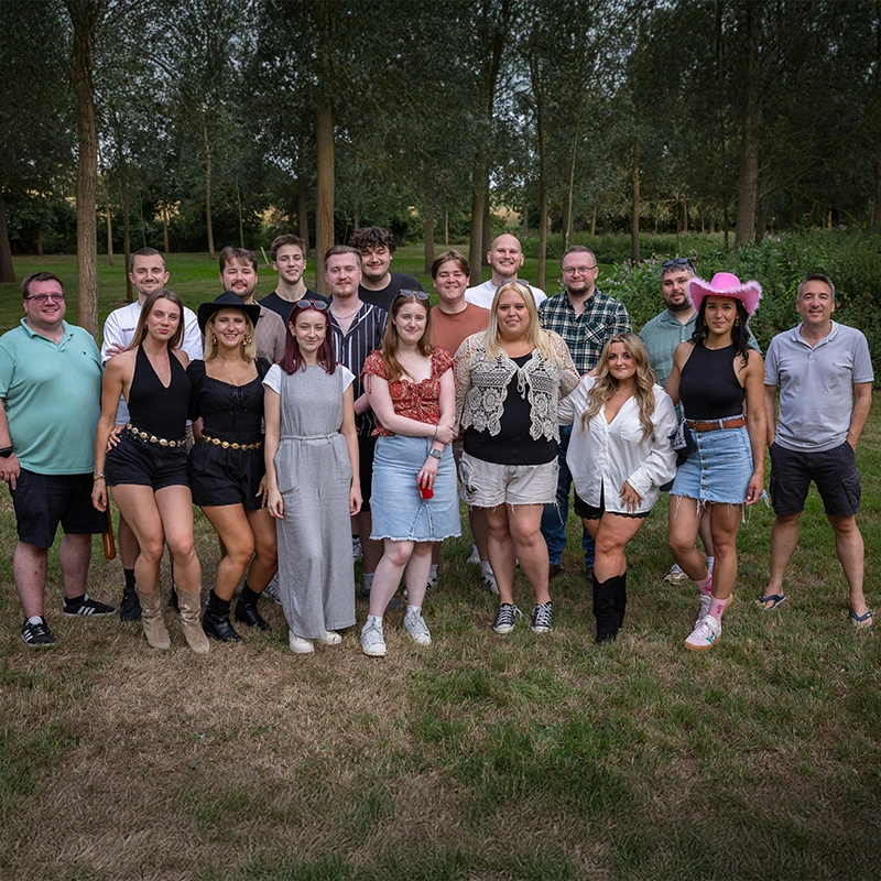 Team photo at summer party standing in front of forest