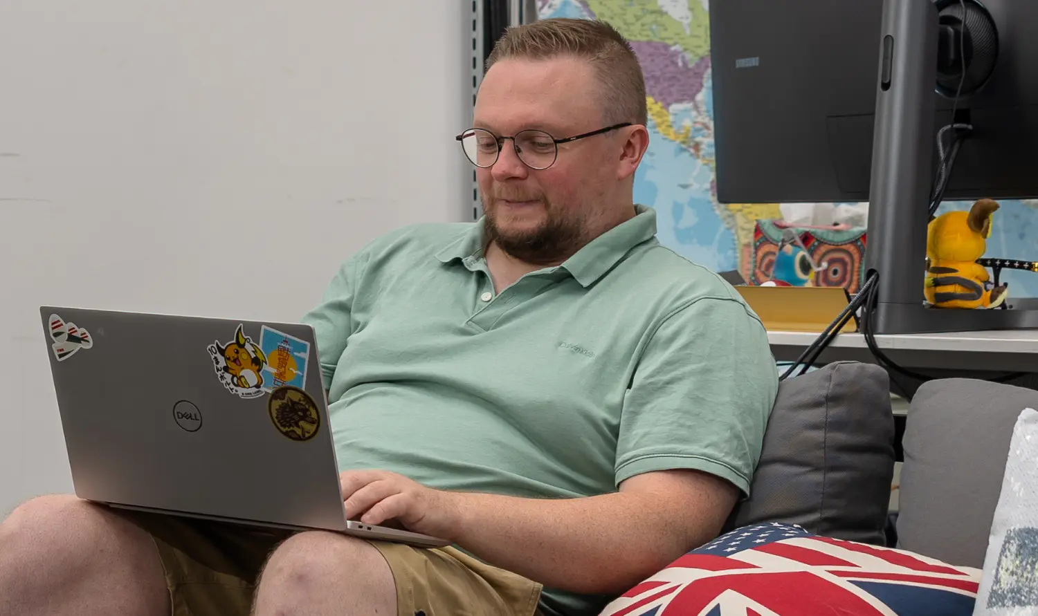 Dave sitting on sofa in Wingman office focused on laptop typing